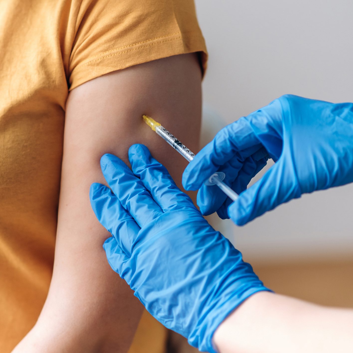 Close-up hands of the doctor wearing protective gloves giving a dose of vaccine to a patient in laboratory. Vaccination of coronavirus infection covid 19, a nurse injecting vaccine into an arm of patient